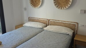 A double bed with a woven headboard, two white pillows, and a patterned bedspread. - Modern Duplex in the Heart of Jaca for 6 People (Jaca)