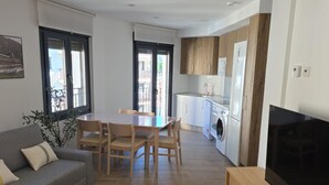 A compact living space with a dining area, sofa, TV, and kitchen. - Modern Duplex in the Heart of Jaca for 6 People (Jaca)