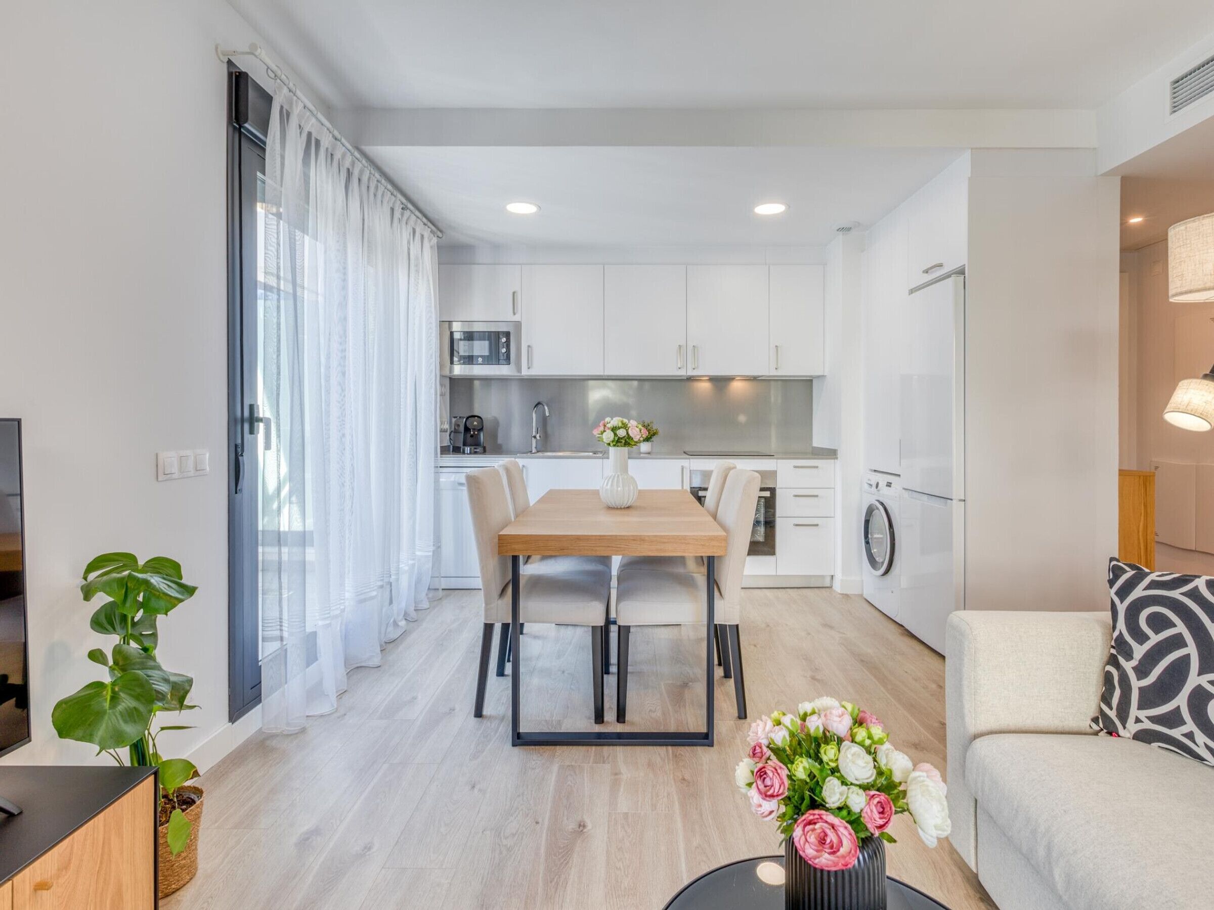 A modern apartment with a dining area, kitchen, and living space.