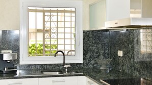 Una cocina con ventana, un lavamanos y un microondas.