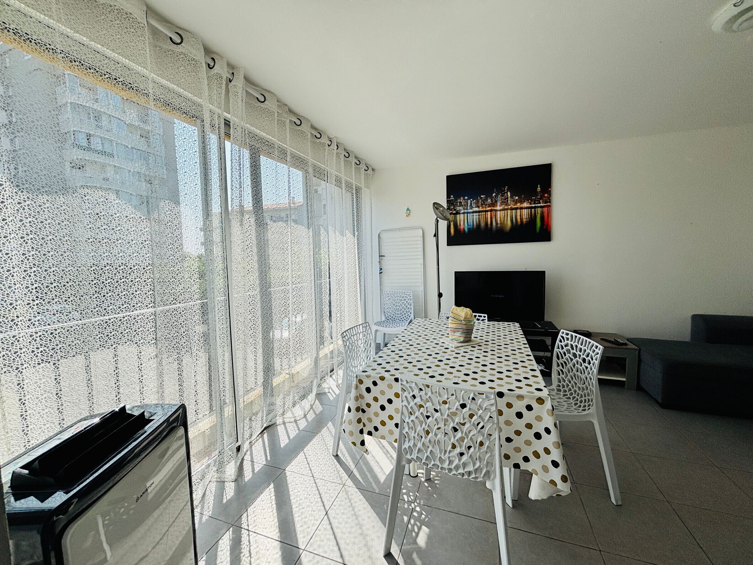 Ein Balkon mit Essbereich, Fernseher und Blick auf die Stadt.