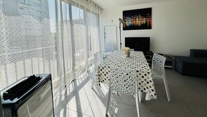Un balcón con comedor, televisor y vista panorámica de la ciudad.