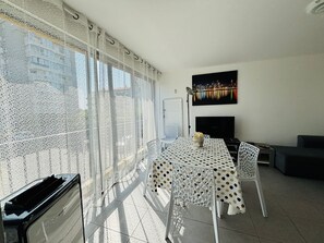 Ein Balkon mit Essbereich, Fernseher und Blick auf die Stadt.