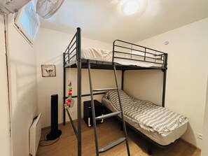 Ein Schlafraum mit Etagenbett, einer kleinen Schreibtisch und einem Wandventilator.