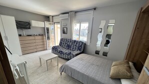 Un dormitorio compacto con cama, sofá, una mesita y un armario.