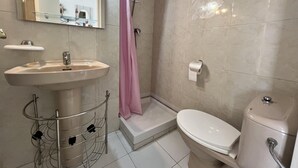 Un baño con lavamanos, inodoro, ducha y espejo.