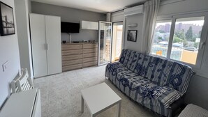 Una sala de estar moderna con un sofá, una mesa de centro, un televisor y un patio corredizo.