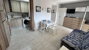 Un espacio habitable compacto con kitchenette, comedor y cama.