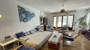 A spacious living room with a sofa, armchairs, a coffee table, and a painting on the wall. - Charming Apartment in Puig Rom, Roses with Parking and Terrace, Sleeps 8 (Roses)