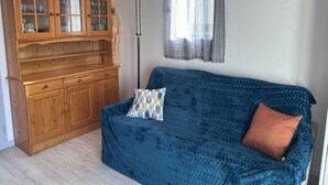 Ein Wohnzimmer mit einem blauen Sofa, einer Holzkabine mit Glastüren und einer Stehlampe.