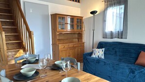 Ein Essbereich mit einem Holztisch, gedeckt für vier Personen, einem blauen Sofa, einem Holzschrank und einer Treppe.