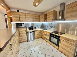 A modern kitchen with wooden cabinets, stainless steel appliances, and a tiled floor. - La Grande Motte: Apt 86m², Air Con, Wi-Fi, Parking, Sleeps 5 (La Grande-Motte)