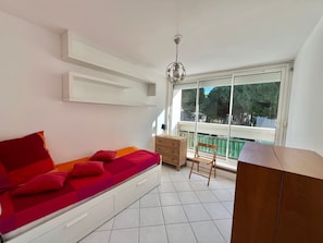 A balcony with a white sofa, a wooden chair, and a small table. - La Grande Motte: Apt 86m², Air Con, Wi-Fi, Parking, Sleeps 5 (La Grande-Motte)