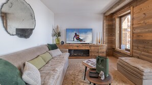 A modern living room with a sofa, coffee table, and a television displaying a skier. - High-end apartment in central location, up to 8 people (Huez)