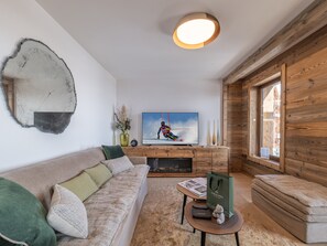 Un salon moderne avec un canapé, une table basse et un téléviseur diffusant une image d’un skieur.
