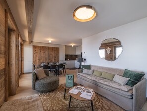 A modern living room with a sofa, a round coffee table, and a dining area with chairs. - High-end apartment in central location, up to 8 people (Huez)
