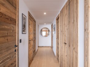 Un couloir avec des portes en bois, un miroir rond accroché au mur et des tableaux encadrés.