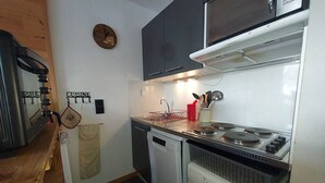 Uma cozinha compacta equipada com micro-ondas, fogão e máquina de lavar roupa.
