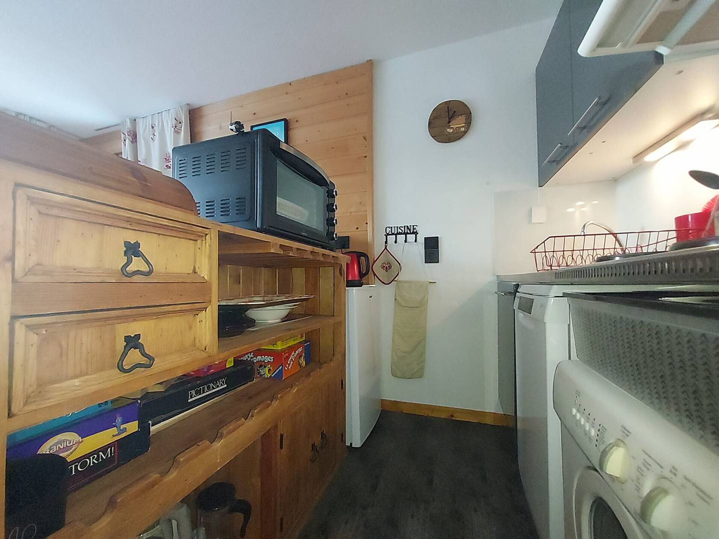 A compact kitchen with a microwave, a refrigerator, and a washing machine.