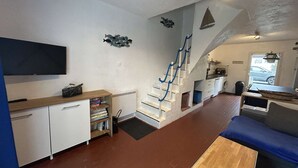 Un espace de vie compact comprenant un escalier, un téléviseur à écran plat, un canapé et un coin cuisine.