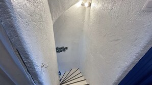 Un escalier étroit, avec un mur blanc et un chambranle de porte bleu.