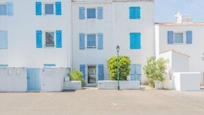 Une rangée de bâtiments blancs aux volets bleus, avec une entrée centrale.