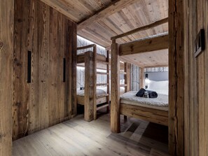 A cabin interior with wooden walls and floors, bunk beds, and a window with a snowy view. - Luxury chalet with wellness - 14 pers, sauna, fireplace (Montvalezan-La Rosière)
