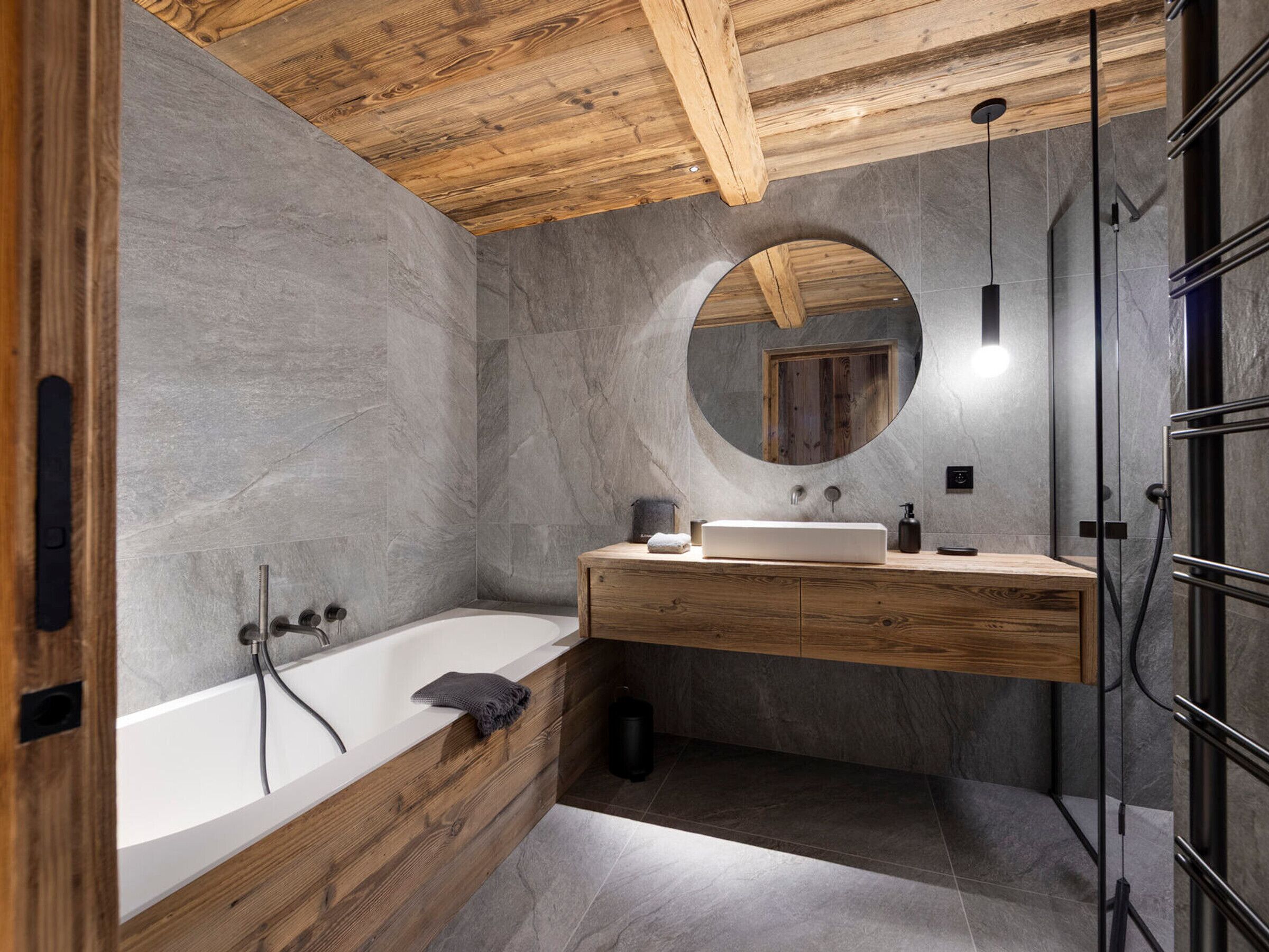 A modern bathroom with a freestanding bathtub, a wooden vanity with a mirror, and a shower area.