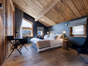 A bedroom with a wooden ceiling, a bed with pillows, a desk, and a chair. - Luxury chalet with wellness - 14 pers, sauna, fireplace (Montvalezan-La Rosière)