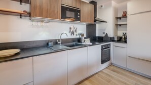 A modern kitchen with wooden cabinets, a stainless steel sink, and a built-in oven. - Modern apartment in Morzine, 6 ppl, Wi-Fi, parking, near slopes (Morzine)