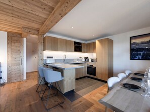Eine moderne Küche mit Holzausstattung, einer zentralen Kücheninsel und einem Essbereich mit Tisch für vier Personen.