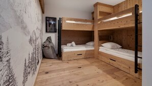 A bunk bed room with wooden walls, a framed picture on the wall, and a large bag on the floor. - Modern 3-bedroom apartment in La Rosière center (Montvalezan-La Rosière)