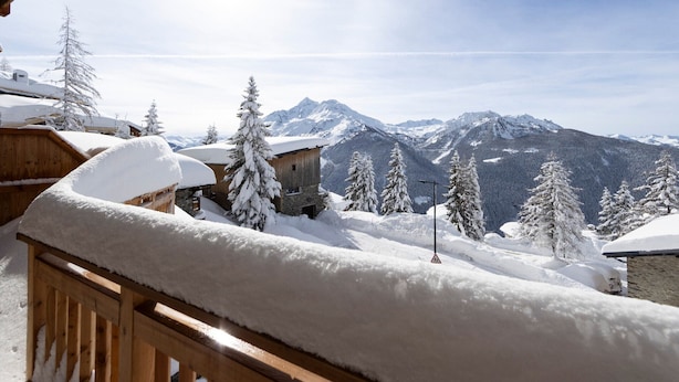 A wooden balcony with snow-covered railings overlooking a mountainous landscape with snow-covered trees and buildings. - Modern 3-bedroom apartment in La Rosière center (Montvalezan-La Rosière)