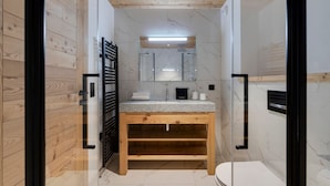A modern bathroom with a wooden vanity, a glass shower enclosure, and a marble-tiled floor. - Modern 3-bedroom apartment in La Rosière center (Montvalezan-La Rosière)