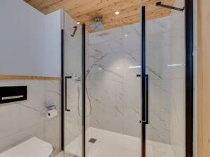 A modern bathroom with a glass-enclosed shower, white marble tiles, and a wooden ceiling. - Modern 3-bedroom apartment in La Rosière center (Montvalezan-La Rosière)