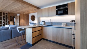 A modern kitchen with wooden cabinetry, a built-in microwave, and a bar area. - Modern 3-bedroom apartment in La Rosière center (Montvalezan-La Rosière)