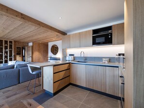 Eine moderne Küche mit Holzschnitzereien, einer eingebauten Mikrowelle und einer Bar.