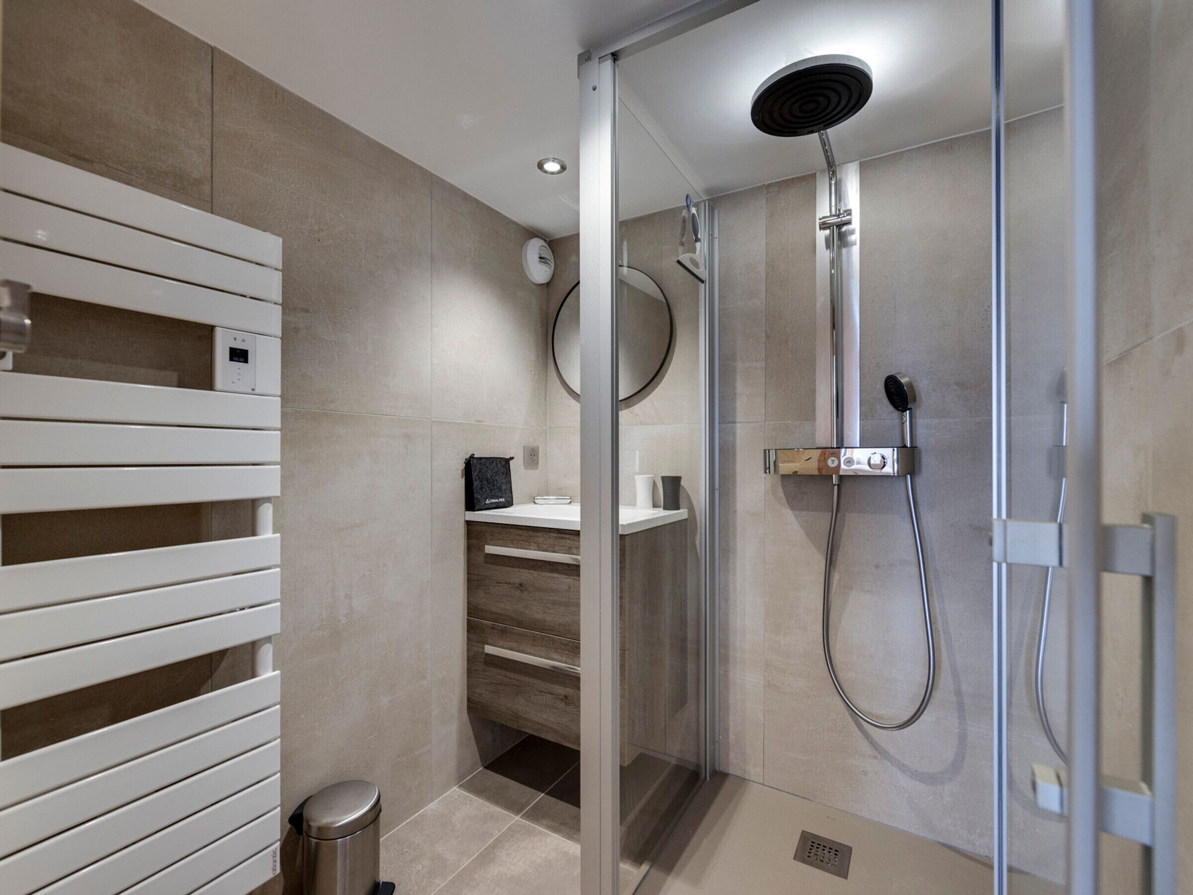 A modern bathroom with a glass shower enclosure, a white vanity, and a towel rack.