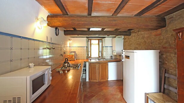 Eine kleine Küche mit Holzbalkendecke, einer Mikrowelle, einem Wasserkocher und einem Kühlschrank.
