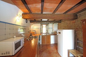Eine kleine Küche mit Holzbalkendecke, einer Mikrowelle, einem Wasserkocher und einem Kühlschrank.