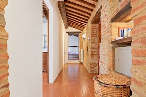 Un corridoio con pareti in mattoni a vista, travi in legno e pavimento piastrellato.