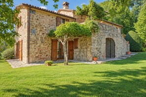 A stone building with a tiled roof, wooden doors, and a small tree in the front yard. - Adriano House, a hillside home with a stunning pool, offering total relaxation and privacy   (Umbria)