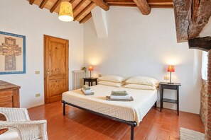 Ein Schlafzimmer mit einem Bett, zwei Nachttischen, einer Holztür, einem Heizkörper und einer Wandlampe.
