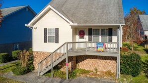 Ein zweistöckiges Haus mit Veranda, Treppe und einem Schild, das eine Immobilienanzeige bewirbt.