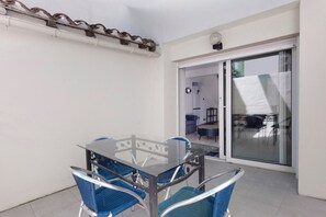 Ein Tisch mit Glasplatte, blaue Stühle, eine Schiebetür aus Glas und eine weiße Wand.