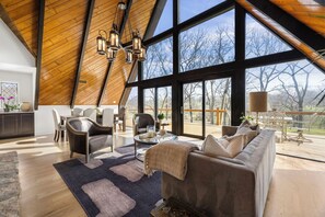 Amplia sala de estar con techo alto, ventanas grandes y vistas al exterior.