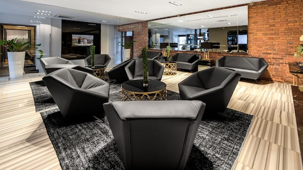 A modern lounge area with black leather sofas, a central coffee table, and a brick accent wall. - Central Kraków Classic King | Ideal for 2 | Free Bfast (Kraków)