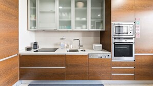 Eine moderne Küche mit Holzschränken, einer Edelstahl-Mikrowelle und einem Backofen.