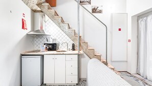 A compact kitchen with a built-in stove, a small refrigerator, and a sink. - GuestReady - The Traveler’s Island (Porto)