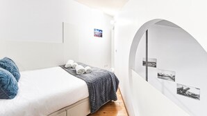 A bedroom with a bed, a small table, and a wall with pictures. - GuestReady - The Traveler’s Island (Porto)